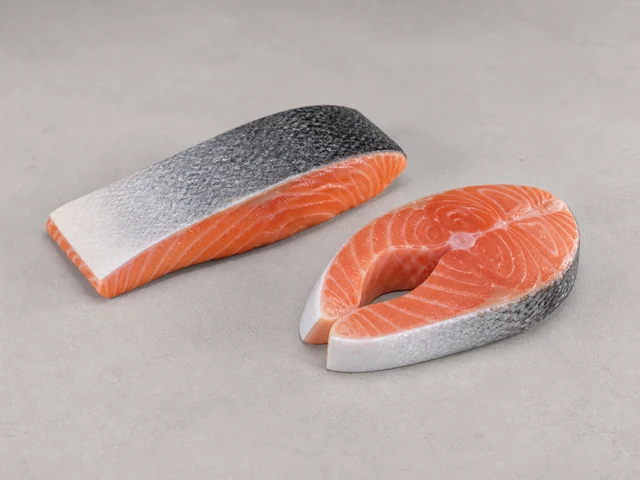 一件無品牌三文魚魚柳和一件魚扒示意，橙粉紅魚肉與淡色脂肪紋可見，實際身份須由標籤確認
