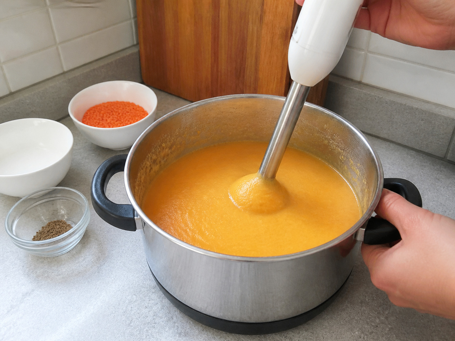 Blend until completely smooth: Keep an immersion blender head below the surface and blend until no carrot pieces or lentil grains remain, moving slowly around the pot.