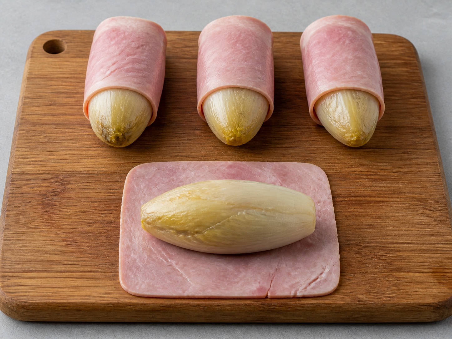 Gratin Endive dan Ham Prancis — Bungkus endive dengan ham: Bungkus setiap endive rapat dengan dua lembar ham.