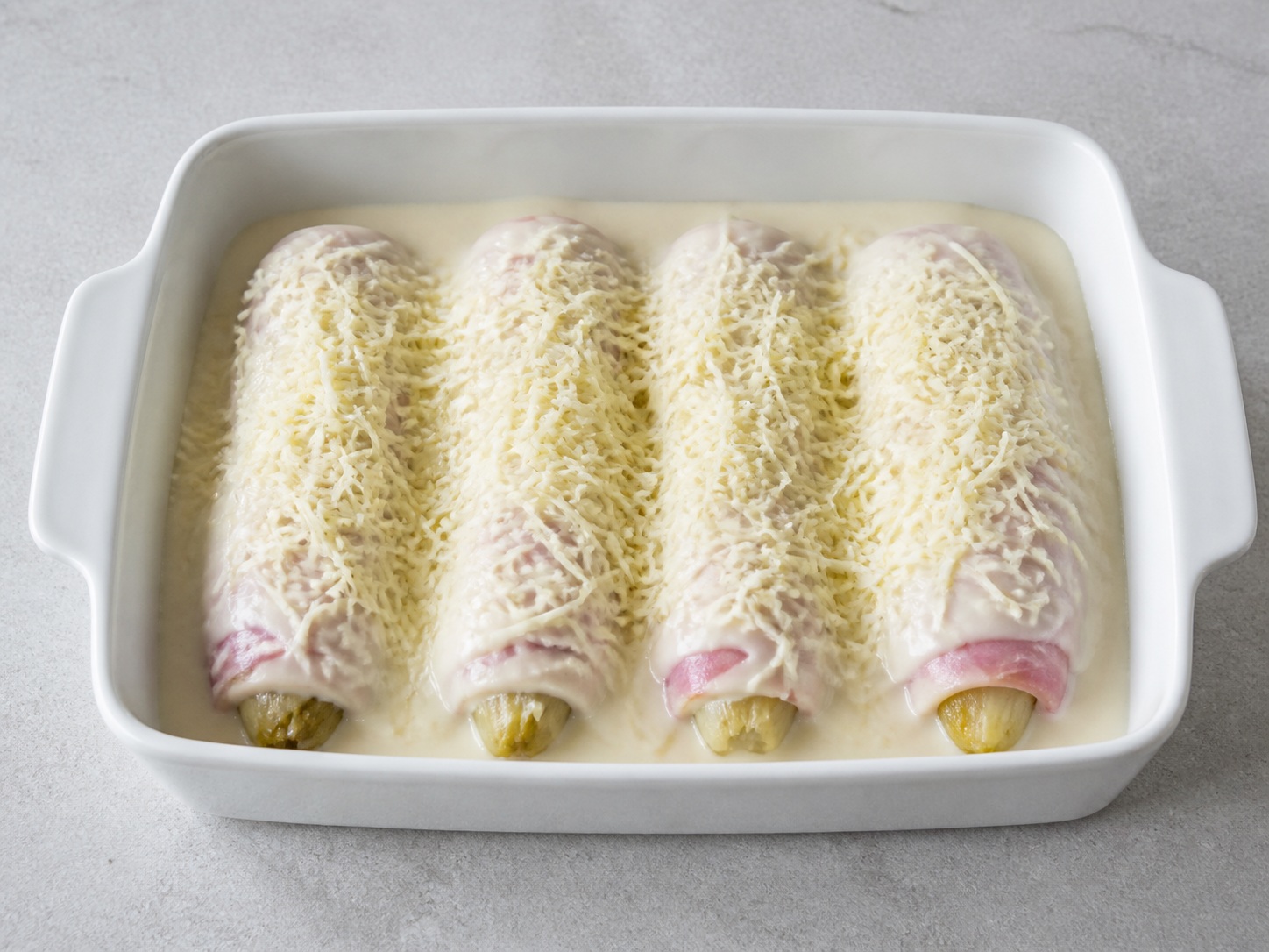 Gratin Endive dan Ham Prancis — Tambahkan keju: Taburkan Gruyère merata di seluruh permukaan.