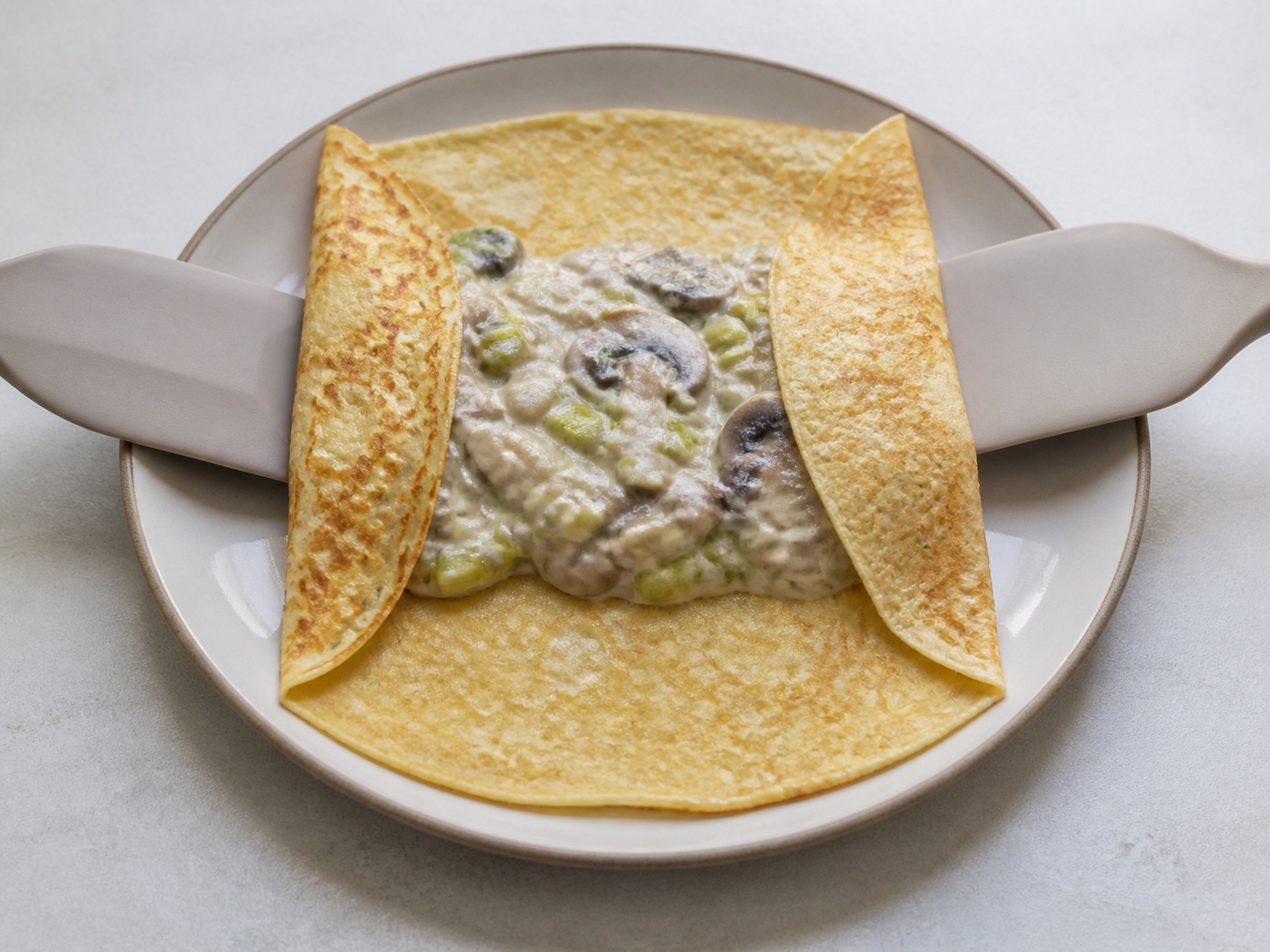 French Mushroom and Leek Crêpes — Fill and fold the crêpes: Spoon filling into each crêpe centre and fold both sides over it.