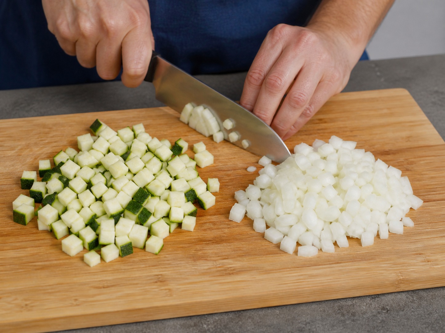 Greek Baked Tomato and Feta Orzo, step 2, Dice the zucchini and onion: Trim 1 zucchini and peel 1 onion, then cut both into even 1 cm dice so they soften at the same rate.