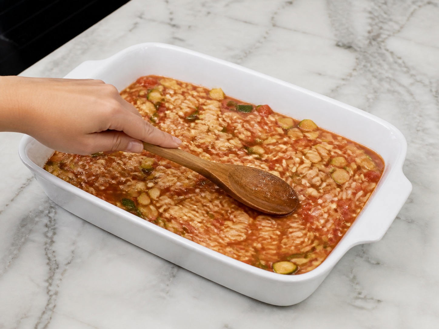 Greek Baked Tomato and Feta Orzo, step 9, Spread in the baking dish: Transfer the wet orzo mixture to the baking dish and spread it into one level layer, keeping all pasta below the liquid surface.