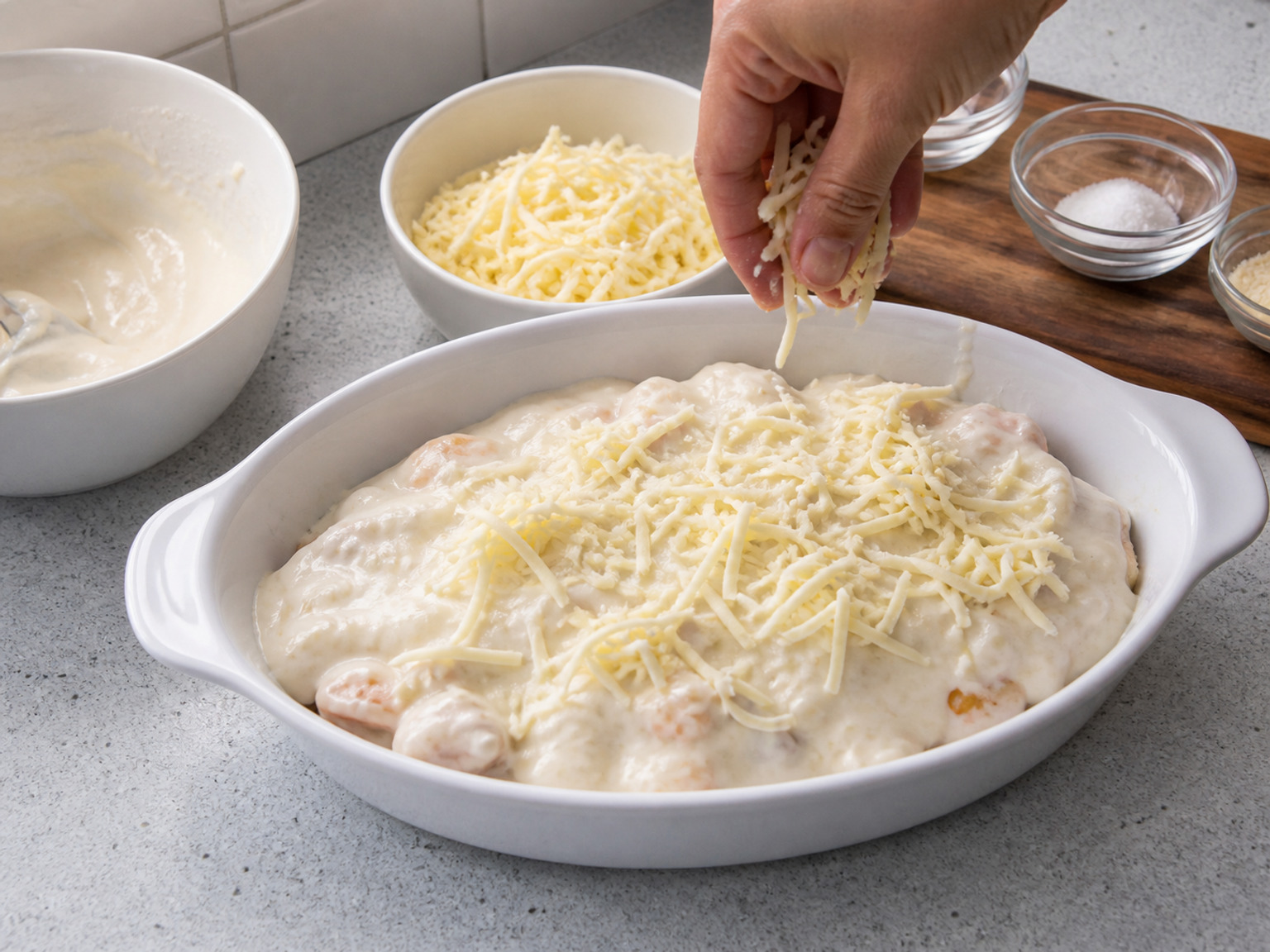 Takpan ng puting sarsa at cheddar: Ibuhos ang buong mainit na puting sarsa hanggang sa gilid ng kanin at lamang-dagat. Ikalat sa ibabaw ang buong 100 g kinudkod na cheddar nang hindi hinahalo sa sarsa.
