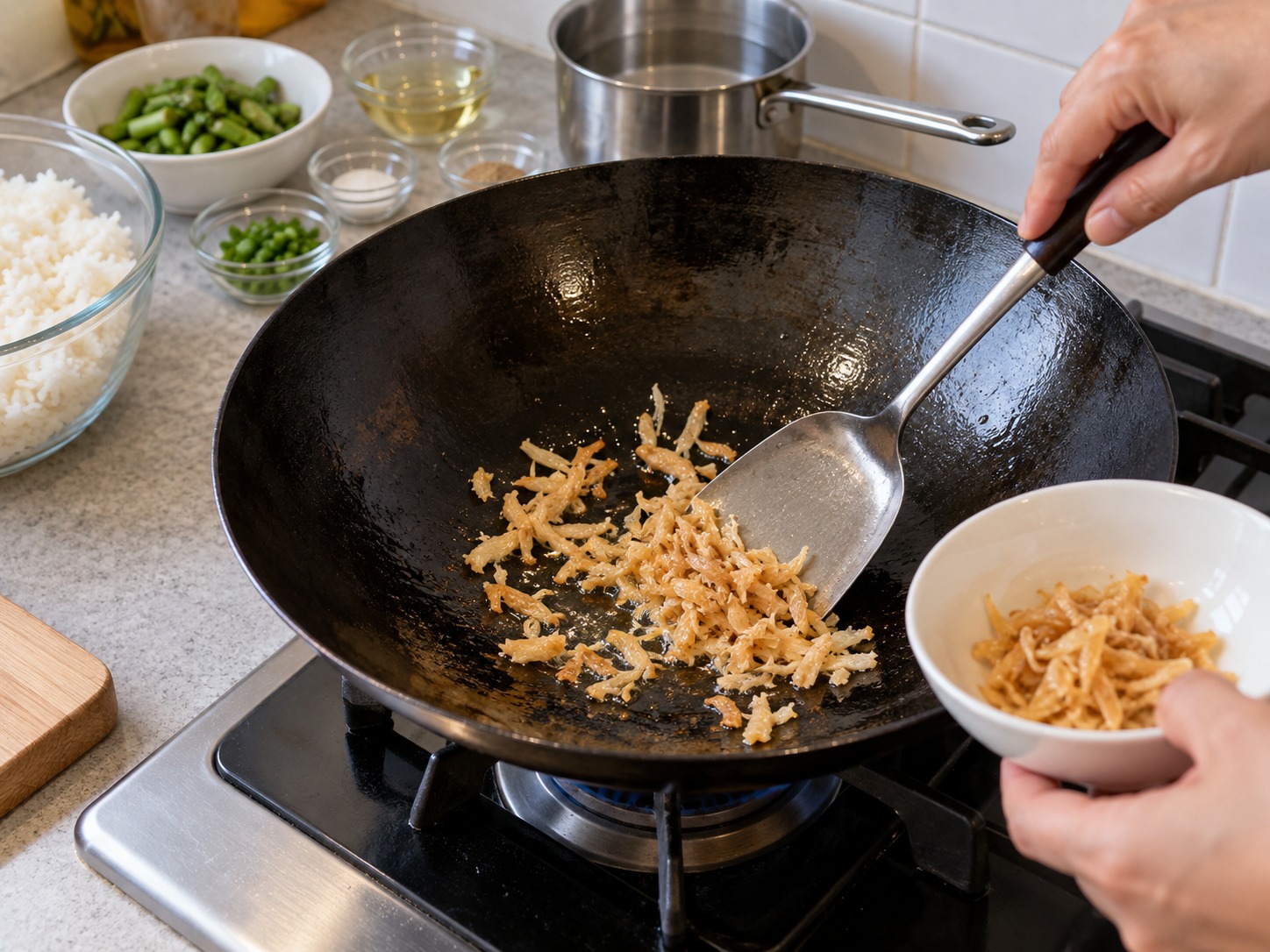 港式瑤柱蛋白炒飯 — 鑊燒熱加一湯匙油，瑤柱絲炒至乾香後盛起