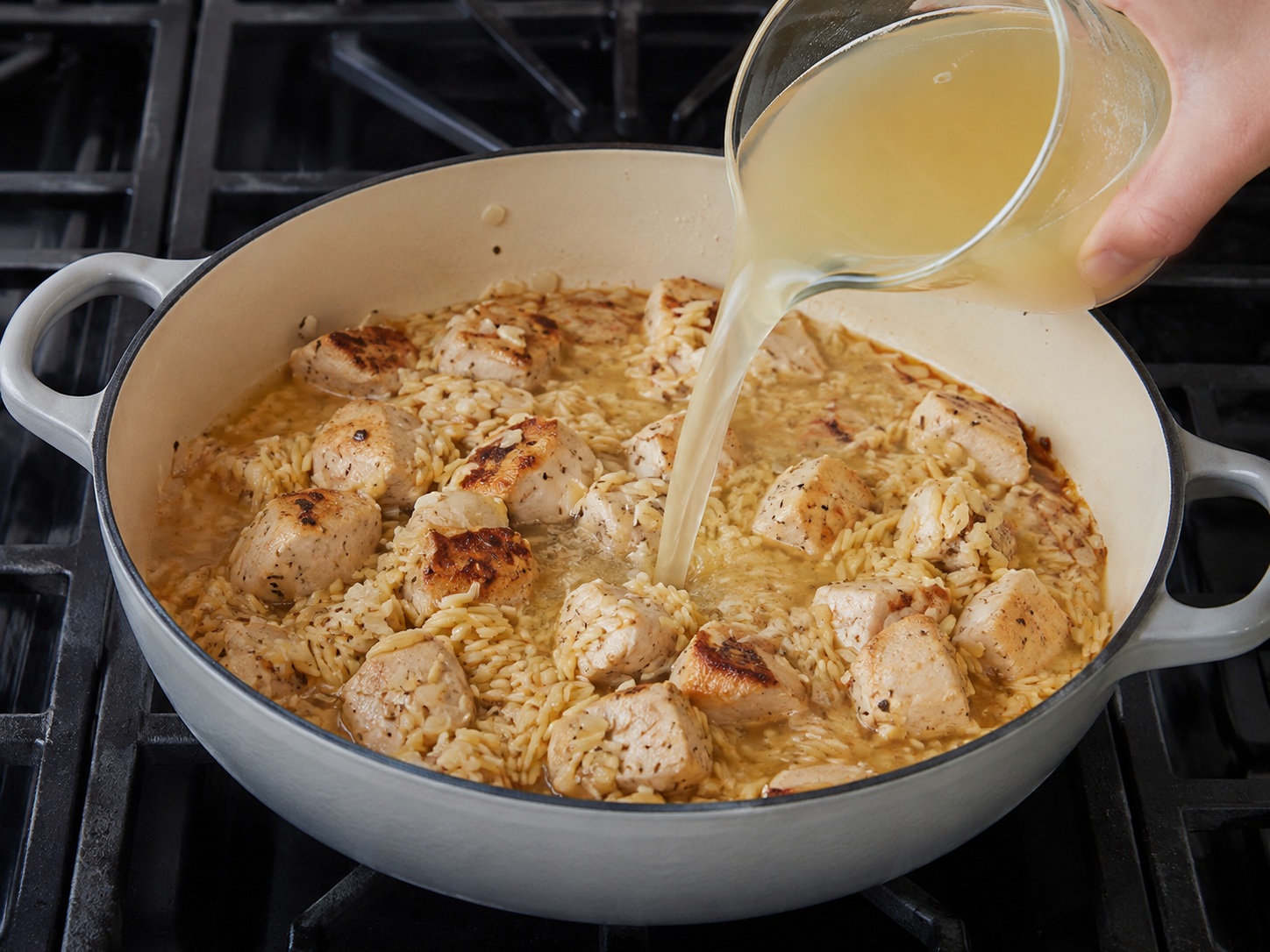 Italian Chicken, Artichoke at Lemon Orzo — Ibuhos ang stock at kaskasin ang ilalim ng palayok, saka ibalik ang browned chicken at katas nito.