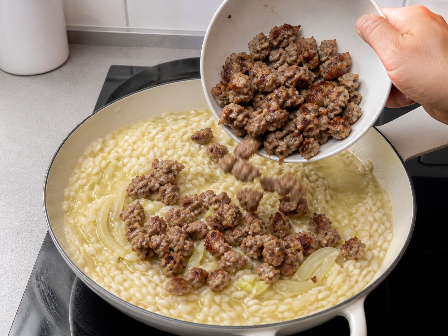 Ibalik ang browned sausage at tikluping ihalo sa risotto nang 2 minuto: Ibalik ang browned sausage at tikluping ihalo sa risotto nang 2 minuto. Gawin nang maingat, sundin ang init, oras at kalagayan ng sangkap, at tiyakin ang pagkakaluto bago magpatuloy.