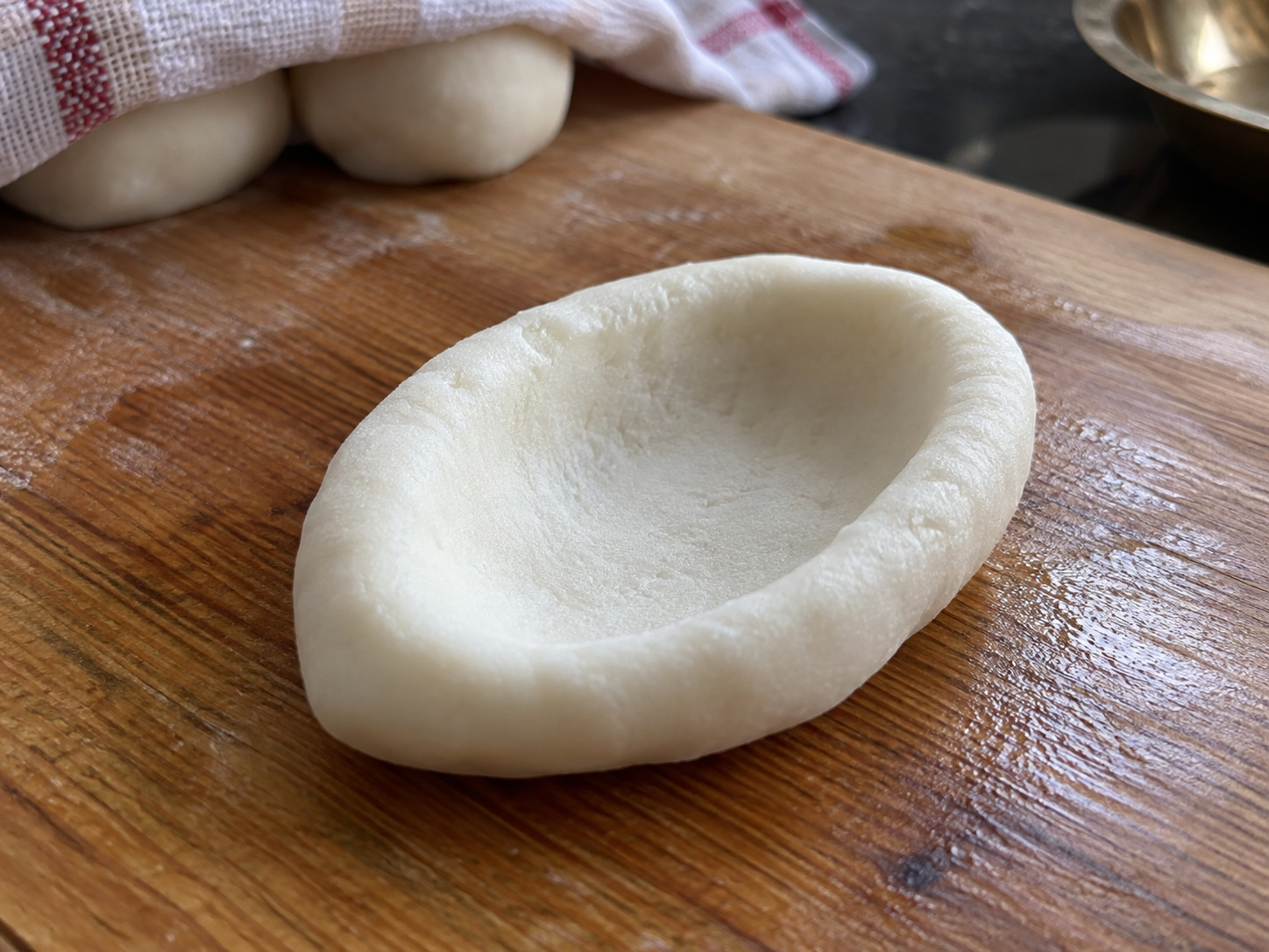 Nepali Yomari — Roll one piece oval and press a deep pocket into its centre with a thumb
