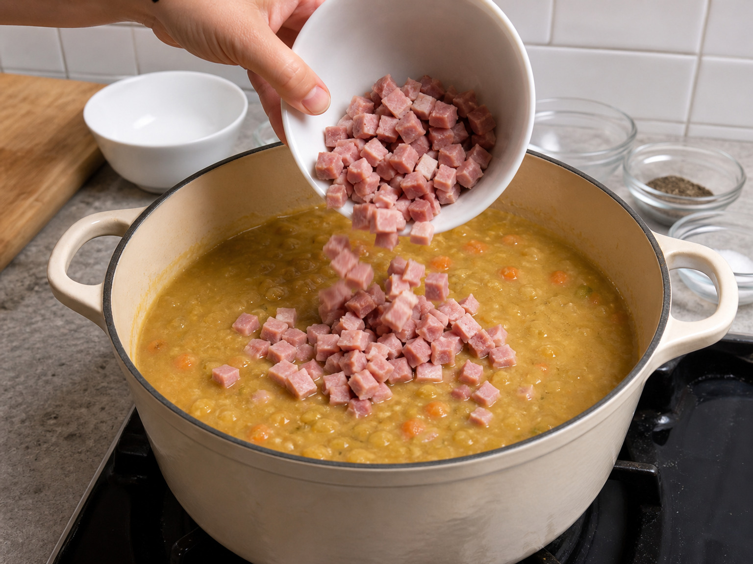 Masukkan seluruh ham: Aduk seluruh 300 g ham potong ke sup kacang kental sampai tersebar rata dan terendam.